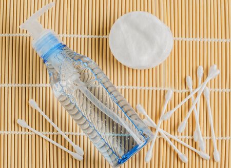 Women's makeup remover accessories. Gel in a transparent bottle, cotton buds, cotton pads on bamboo Mat.の写真素材