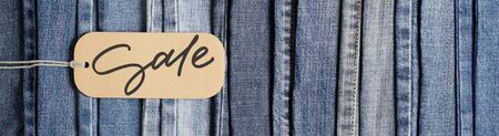 Denim. Blue jeans background. Sale - handwritten inscription on a paper label