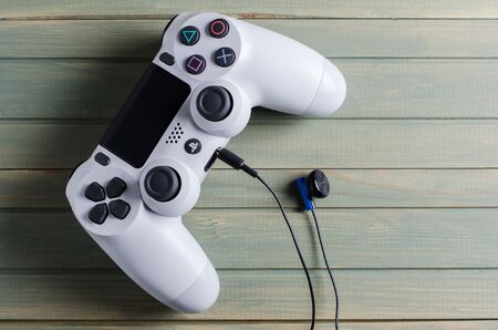IZHEVSK, RUSSIA - 17 OCTOBER, 2019: White PlayStation 4 game console joystick with earphone.