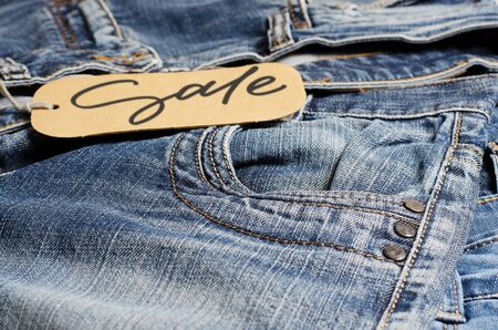 Denim. Blue jeans on the store counter. Sale - handwritten inscription on a paper label.の写真素材