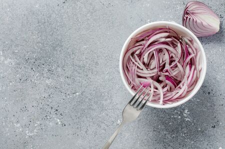 Pickled chopped red onion in vinegar in a white plate. A delicious side dish for meat and fish dishes. Light grey background. Flat top viewの写真素材