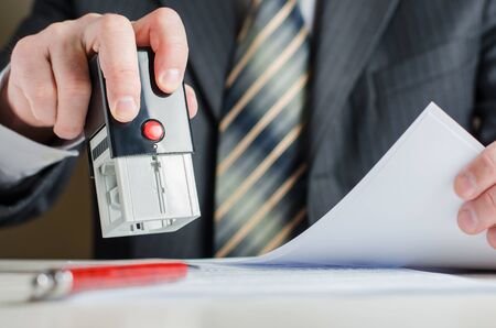 A lawyer or notary puts a seal on the document. A stamp in a man's handの写真素材