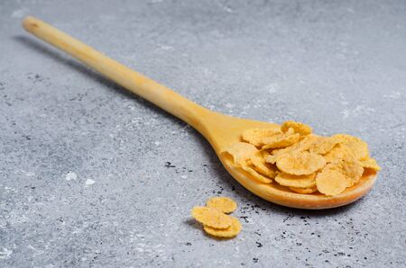 Corn flakes in a wooden spoon. Concrete background. Flat top view. Copy space.の写真素材