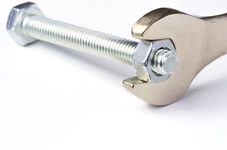 The wrench unscrews the nut on the bolt. White background. Copy space