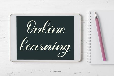 Online learning - handwritten inscription on a tablet. The concept of distance training for children. White wooden backgroundの写真素材