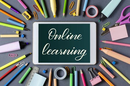 Online learning - handwritten inscription on a tablet. The concept of distance training for children. Tablet and office supplies on a dark backgroundの写真素材