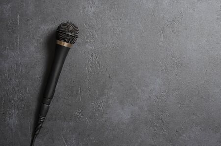 Black microphone on a dark concrete background. Equipment for vocals or interviews or reporting. Copy space.の写真素材