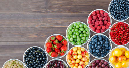 A set of berries in the round plates. Brown wooden background. Copy spaceの写真素材