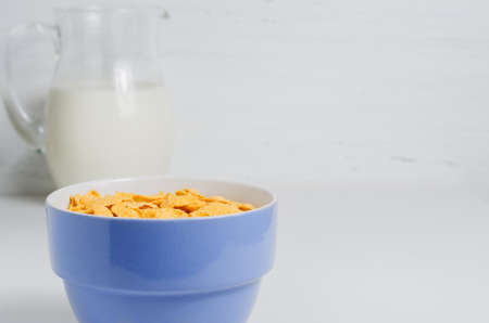 Milk in a glass jug and corn flakes. The concept of natural and healthy food. White background. Copy...