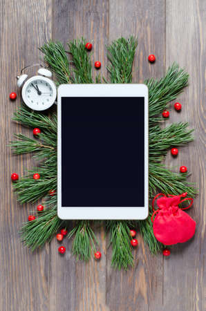 Christmas or new year background on a wooden background. Tablet with a blank screen for greetings....