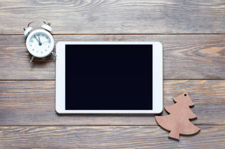 Christmas or new year background on a wooden background. Tablet with a blank screen for greetings. Flat lay, top view, copy space.の写真素材
