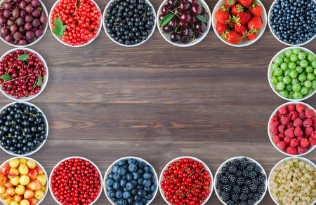 A set of berries in the round plates. Brown wooden background. Copy space. Flat top view.の写真素材