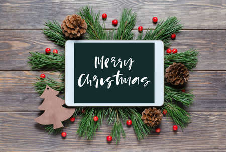 Christmas or new year background on a wooden background. Handwritten inscription on the gadget screenの写真素材