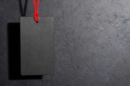 Black tag hanging. Dark concrete background. The concept of the holiday sales on black Friday. Copy spaceの写真素材