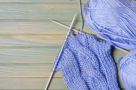 Balls of blue yarn and knitting needles. Wooden background. Copy space. The concept of women 's...