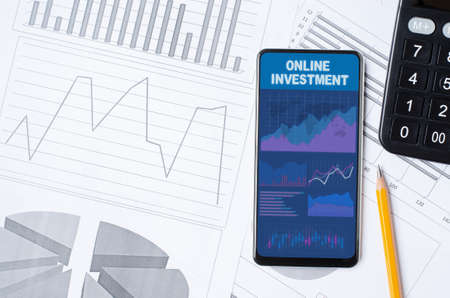 Online investment. Smartphone with a mobile app on the background of graphs and charts. Copy spaceの写真素材