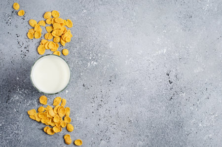 Corn flakes on a concrete background and milk in a glass. Flat top view. Copy space
