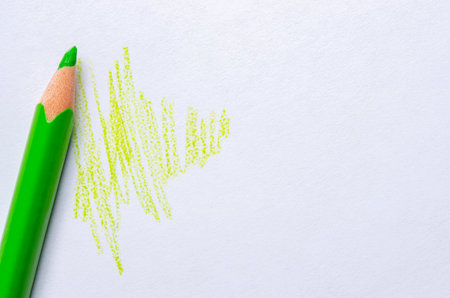 A green pencil draws strokes on white paper. Copy spaceの写真素材