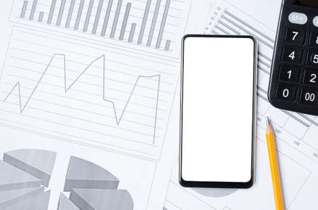 Smartphone with a blank screen on the background of graphs and charts. Copy space. The concept of...