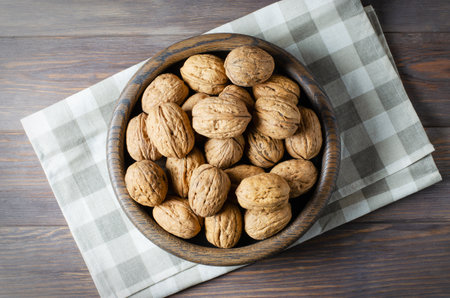 Walnuts in a plate on a brown wooden background. Nuts are a source of vegetable protein. Flat top viewの写真素材