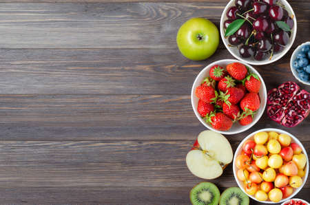 Mix of fresh berries, nuts and fruits. Healthy food contains a lot of vitamins and useful trace elements.Brown wooden background. Copy space.の写真素材