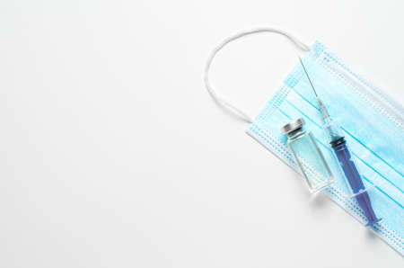 A syringe and a medical mask on a white background. The concept of protection and vaccination...