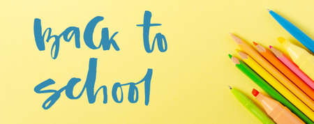 Back to school. Handwritten inscription. School supplies on a yellow paper background