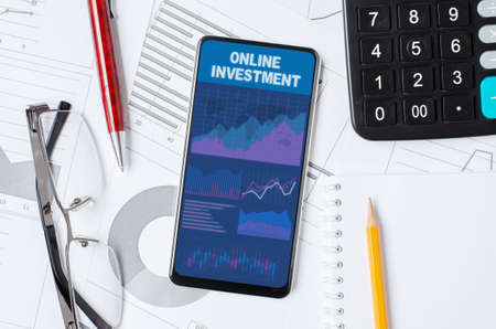Online investment. Smartphone with a mobile app on the background of graphs and charts.の写真素材