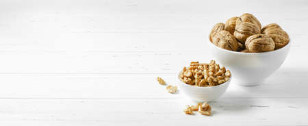 Walnuts in a plate on a white wooden table. Copy space