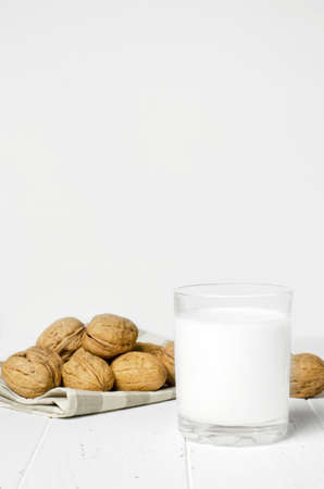 Milk from walnuts and nuts on a white wooden background. Products containing vegetable protein, vitamins, and useful amino acids. Copy space.の写真素材