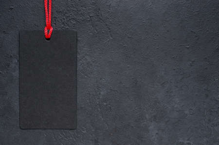 Black tag hanging. Dark concrete background. The concept of the holiday sales on black Friday. Copy spaceの写真素材