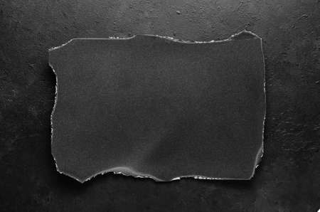 Black burnt paper on a dark concrete background. Design elements or portfolio. Copy spaceの写真素材