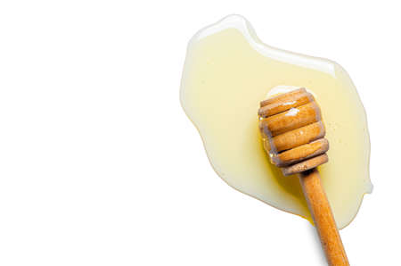 Spilled fresh honey with a wooden spoon. White background. Copy spaceの写真素材