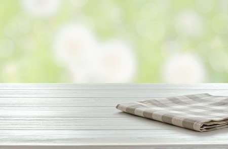 An empty white wooden table. Blurry summer or spring background.