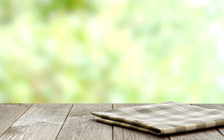 An empty brown wooden table. Blurry summer or spring background.