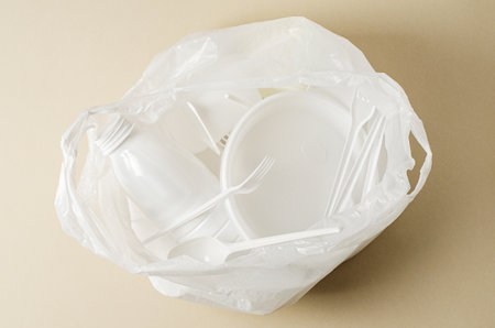 Disposable tableware in a white plastic bag. The concept of pollution of nature.