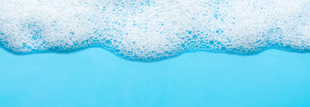 Texture of white foam on a blue background. Cleansing mousse for the face or bath foam or washing powder. Closeup. Copy spaceの写真素材