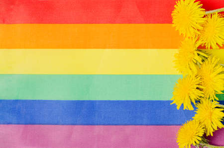 Rainbow flag and yellow flowers. A symbol of the LGBT community. Copy spaceの写真素材