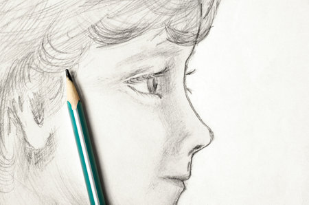 A childs face drawn in pencil. Sketch on paper. The concept of learning to drawの写真素材