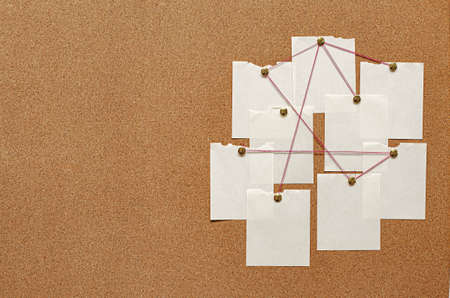 Blank paper notes are pinned to a cork board. The concept of detective investigation. Copy space.の写真素材