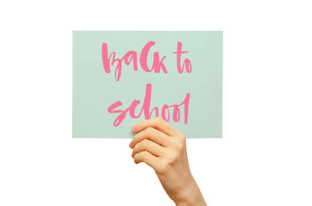 A colored poster in the girls hand. Handwritten inscription Back to school. Isolated on whiteの写真素材