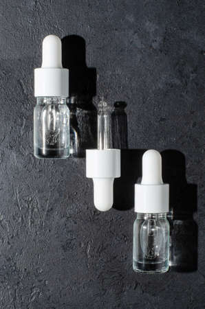 Cosmetic product in a bottle with a pipette. Serum for skin or hair. Black concrete background.の写真素材
