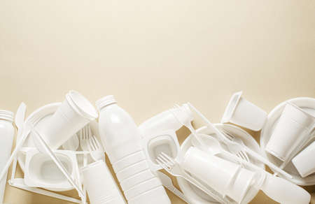 Disposable white plastic tableware on a beige background. The concept of nature pollution. Copy space.の写真素材