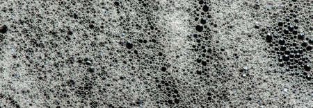 Texture of white foam on a black background. Cleansing mousse for the face or shaving foam or...