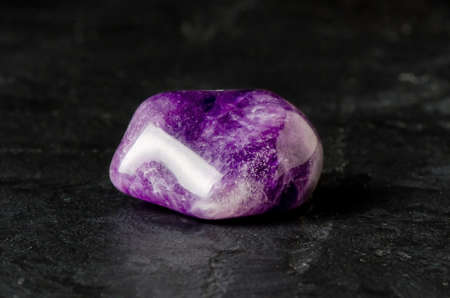 Amethyst mineral on a black concrete background. The concept of using minerals and crystals in astrology and alternative or complementary medicine.の写真素材