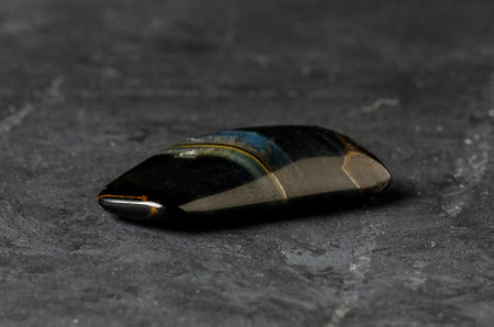 The stone is a mineral on a black concrete background. The concept of using minerals and crystals in astrology and alternative or complementary medicine.の写真素材