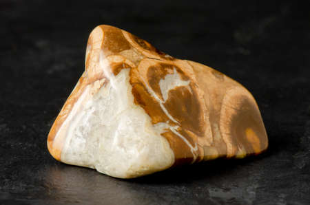 The mineral stone is realite on a black concrete background. The concept of using minerals and crystals in astrology and alternative or complementary medicine.の写真素材