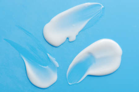 A sample of white moisturizer on a blue background. Cosmetic product for the skin.