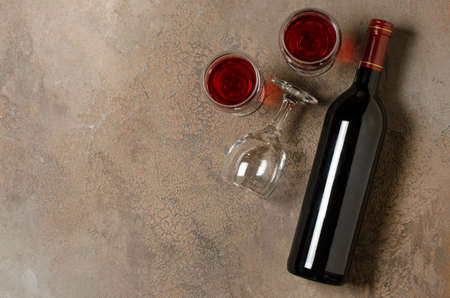 Red wine in a bottle. Brown concrete background. Flat lay. Copy space.