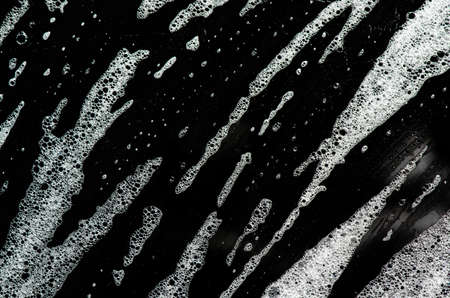 Texture of white foam on a black background. Cleansing mousse for the face or shaving foam or washing powder. Closeupの写真素材